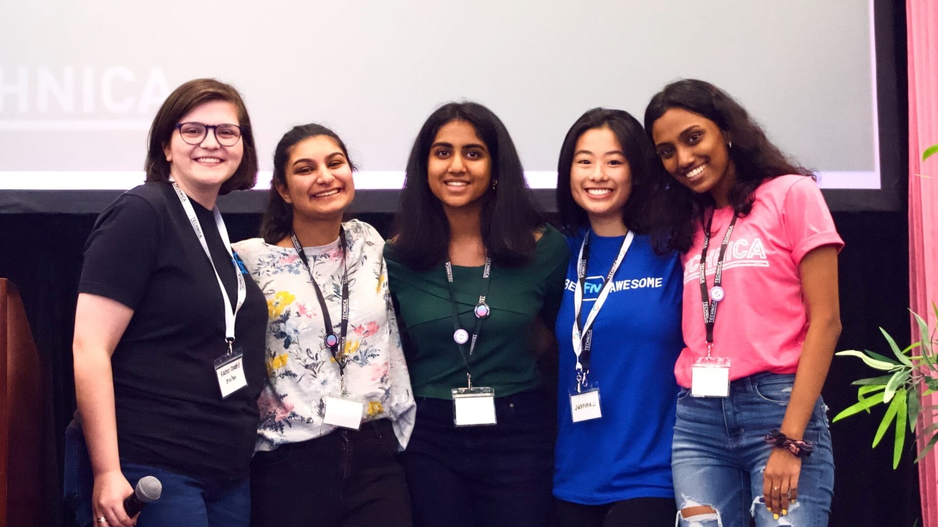 A group photo of 5 winning-hackers smiling and standing on stage at the awards ceremony.